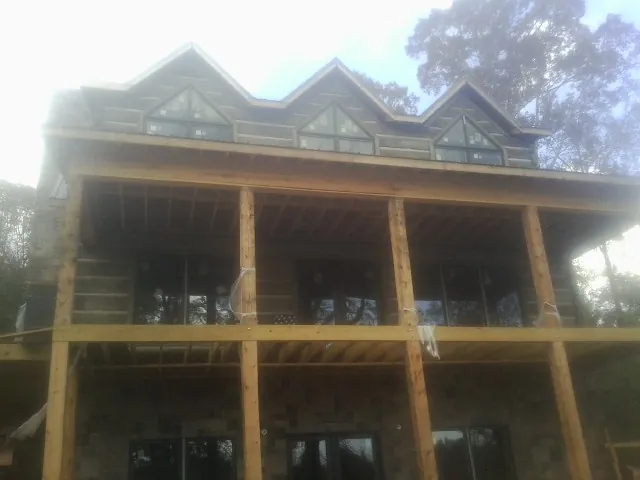 Dormers and porch framing on a large log home under construction — Roof Coating work by our crew in Moulton