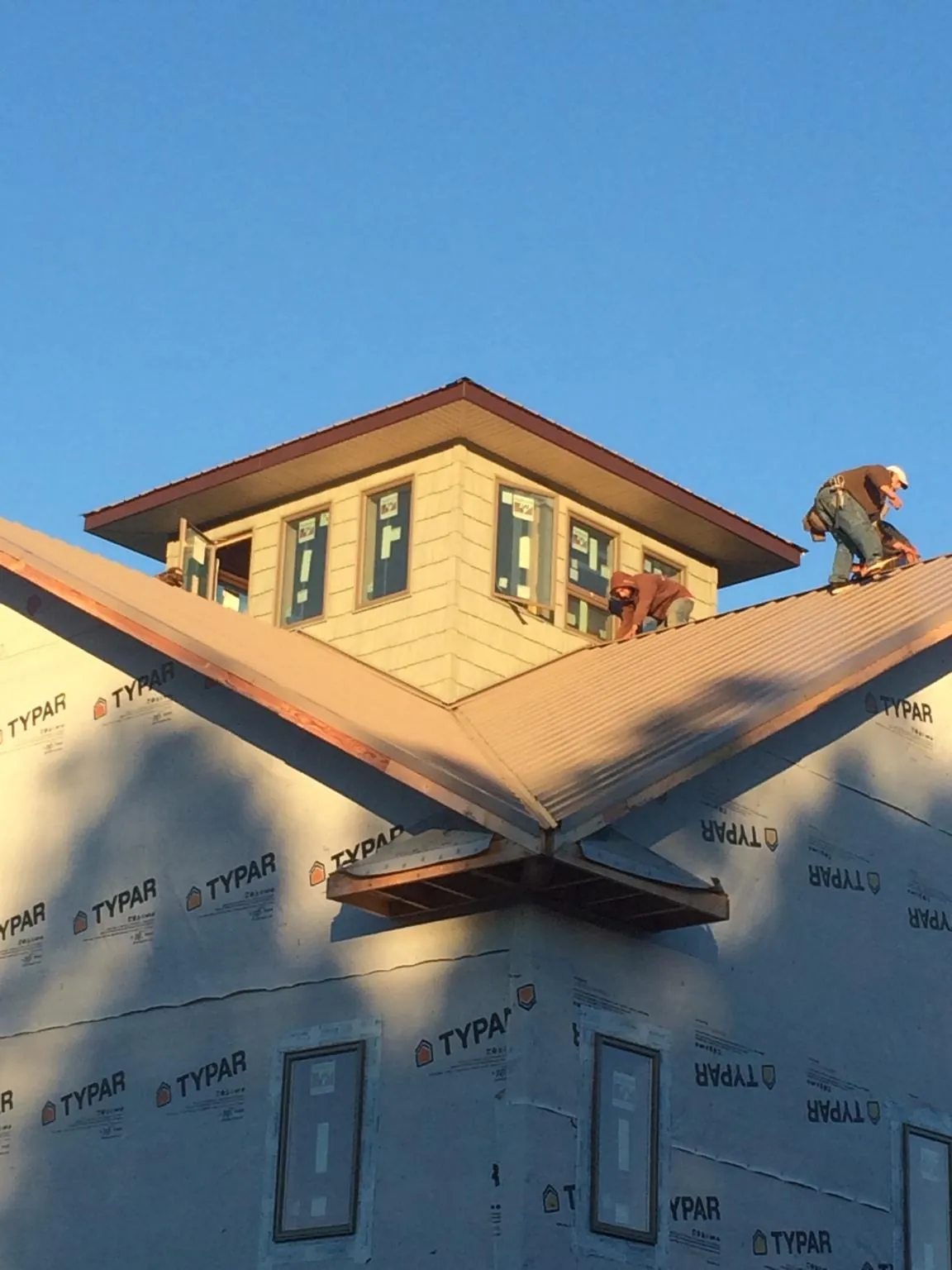 Roofers working around a rooftop cupola on a new metal roof at sunset — Roof Waterproofing in Moulton by Roofing Brothers
